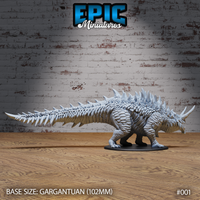 Same heavily armoured beast facing right, showing the broad scaled back, layered dorsal ridge spines tapering along the full length of the spiked tail, and thick clawed haunches. Mounted on a 102mm round base. Sculpt by Epic Miniatures.