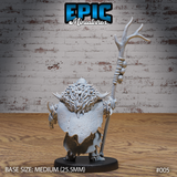 Orc shaman seen from behind, revealing a thick mane of spiked fur across broad shoulders, a rough hide cloak, and the raised antler staff crowned with branching tines. Sculpt by Epic Miniatures.