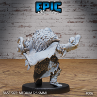 Orc shaman seen from behind, revealing a thick shaggy fur mantle covering the back and shoulders, with bone spurs and fetish details visible along the fur edges. Both arms raised outward, cord-wrapped forearms prominent. Sculpt by Epic Miniatures.