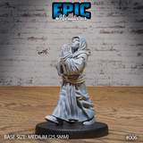 Hooded robed figure, hands pressed together in prayer, gazing upward with an intense expression, holding a tome to his chest, rope belt cinched at waist. Sculpt by Epic Miniatures.