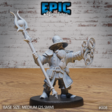 Stocky dwarf wizard raising an ornate flame-topped staff in one hand, conjuring interlocking arcane rings with the other, wearing layered armour, a broad hat, and a heavy robe. Sculpt by Epic Miniatures.