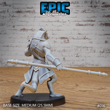 Lizardfolk monk viewed from behind, showing broad scaled shoulders, cross-body armour straps, layered back plating, and a low spear held horizontally at hip height. Dense scale texture visible across legs and tail. Sculpt by Epic Miniatures.