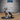 Young white dragon miniature standing upright on a 51mm oval base, head lowered in an alert posture, wings swept back, long serrated tail arcing behind. Heavily scaled body with crest of horns. By Epic Miniatures.