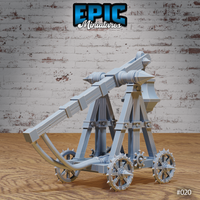 Trebuchet terrain model showing the throwing arm raised at a steep angle, torsion spring mechanism visible at the base, spiked wheels, and crossed timber support structure. Sculpt by Epic Miniatures.