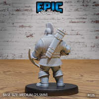 Dwarven crossbowman viewed from behind, showing a large cylindrical bolt case strapped across his back with buckled leather harness. Scale mail covers the full torso, mohawk crest visible from above. Sculpt by Epic Miniatures.