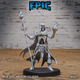 Skeleton wizard standing upright, raising a skeletal hand wreathed in arcane flame, gripping a tall orb-topped staff. Ragged hooded robes expose bare ribs. Sculpt by Epic Miniatures.