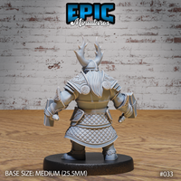 Dwarf warrior seen from behind, revealing quilted scale skirt panels beneath plate armour, Celtic knotwork on shoulder guards, antlered helmet rising from a horned nasal helm, and square hammer heads visible at each side. Sculpt by Epic Miniatures.