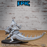 Lizardfolk rider wearing layered armour with a raised dorsal crest, gripping a curved horn, seated atop a heavily textured crocodilian with a long spike-ridged tail. Sculpt by Epic Miniatures.