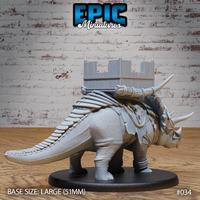 Rear view of the armoured triceratops showing scaled tail, rope-lashed saddle rigging, and the four-posted timber battle platform with spiked battlements mounted across its back. Sculpt by Epic Miniatures.