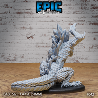 Crystal Drake Attack by Epic Miniatures — rear view showing the full ridge of angular crystal prisms running down the spine and back, tightly scaled body coiled low, head raised with open jaws, one clawed foot raised, long segmented tail trailing to the right on a large oval base.