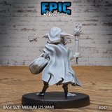 Hooded goblin seen from behind, cloak billowing outward to reveal the full drape of the fabric, satchel visible under one arm and flaming torch raised in the other hand, bare clawed feet planted in a wide forward stride. Sculpt by Epic Miniatures.