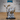 Stocky bearded dwarf mage facing forward, raising one hand to conjure swirling flame while gripping a tall staff topped with a winged dragon head. Long layered robes, spectacles, and a rope belt. By Epic Miniatures.