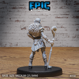 Female hobgoblin from behind, showing a voluminous layered fur cloak covering her back and shoulders, with armour plates visible at the sides and the wrapped base of the skull staff held low. Sculpt by Epic Miniatures.