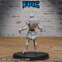Hobgoblin female miniature seen from behind, showing a voluminous braided fur cloak cascading down the back, dual daggers held low at each side, wrap-bound legs and spiked pauldrons. Sculpt by Epic Miniatures.