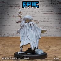 Hobgoblin female sorcerer seen from behind, large billowing cloak dominating the silhouette with worn fabric detail, runic gauntlet arm raised above the hood, armoured legs visible below the cape hem, cobblestone rubble base. Sculpt by Epic Miniatures.