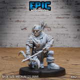 Kneeling female orc archer gripping a spear horizontally, wearing a patched travelling cloak and leather armour, quiver of arrows strapped to her back, grim determined expression. Sculpt by Epic Miniatures.