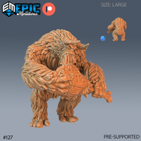 Digital render of an unpainted large-scale resin yeti miniature by Epic Miniatures — the creature crouches forward, arms wrapped around a large haunch of meat, gnawing at the bone with a wide-open snarl. Two curved horns rise from its heavily textured shaggy head. A size comparison shows a standard d20 and a smaller 32mm figure alongside the model, confirming its large scale.