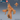 Digital render of a large horned yeti miniature from Epic Miniatures, shown in orange resin. The beast stands with arms spread wide and mouth open in a roar, heavy iron shackles and chains bolted around each wrist. Thick layered fur covers the body with exposed abdominal muscle visible beneath. Spiralling horns crown the head. A small rear-view reference and a blue d20 for scale are shown in the upper right corner.
