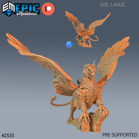 Armoured griffin with wings spread wide, eagle head raised and snarling, ornate chest barding with scrollwork detail, talons gripping a rocky scenic base. Sculpt by Epic Miniatures.