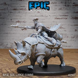 Warrior with braided hair and beaded jewellery riding a saddled war-rhino, spear levelled forward, cape swept back, large saddlebags and bedrolls secured behind. Sculpt by Epic Miniatures.