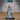 Female spellcaster raising a dagger overhead with both arms, wearing a tall wrapped headdress, feathered collar, and flowing robes with a crescent moon chain belt. Sculpt by Epic Miniatures.
