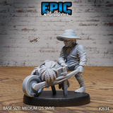 Halfling villager leaning forward to push a wooden wheelbarrow loaded with large leafy cabbages, wearing a wide-brimmed hat, buttoned coat, and bare hairy feet. Sculpt by Epic Miniatures.