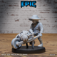 Halfling villager leaning forward to push a wooden wheelbarrow loaded with large leafy cabbages, wearing a wide-brimmed hat, buttoned coat, and bare hairy feet. Sculpt by Epic Miniatures.