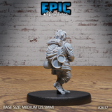 Halfling miniature seen from behind, showing a tightly rolled bedroll, round water vessel, tin cup, and traveller's pack strapped across the back. Bare hairy feet visible at base. Sculpt by Epic Miniatures.