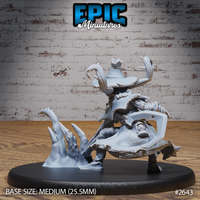 Pumpkin-headed scarecrow mage viewed from behind and below, revealing a large cleaver or axe-like blade at the hip, layered ragged robes, and the erupting icy crystal base piece to the left. Epic Miniatures sculpt.