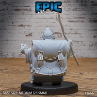 Hamster mage miniature seen from behind, revealing a large buckled backpack across broad robed shoulders, one hand raised with fingers splayed, gnarled staff held upright. Sculpt by Epic Miniatures.