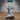 Dragonborn priest in sweeping ornate robes, holding an open spellbook in one hand and reaching forward with a clawed hand mid-cast, wearing a fearsome open-jawed draconic helm, standing on a rocky scenic base. Sculpt by Epic Miniatures.