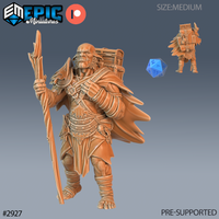 Digital render of an unpainted hobgoblin adventurer miniature at 32mm scale, shown in terracotta resin tone. The figure stands in a confident mid-stride pose, holding a tall gnarled staff in one hand and wearing a billowing travel cloak. A large wooden-framed pack is strapped to his back. He wears a studded belt with a skull charm, layered travelling clothes, and wrapped leg bindings. A blue d20 and a rear-view of the miniature are visible alongside the main figure. Epic Miniatures logo in top-left corner.