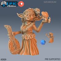 Digital render of an unpainted resin 32mm goblin bard miniature — she wears a rope skirt and layered rope jewellery, holds a maraca aloft in one hand, and carries a bamboo lute at her side, with a roaring tiger skull headdress atop her head; a scale d20 and smaller size-reference figure are visible beside her