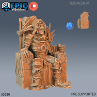 Digital render of a half-goblin Bandit King miniature seated on a crumbling stone throne, wearing spiked leather and plate armour with a hood, one hand resting on his knee and a chained orb at his waist, with a staff propped at his side — shown in unpainted resin orange-tan colouring with a d20 and stone pillar fragment for scale
