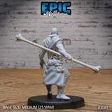 Bald, broad-shouldered monk seen from behind, bone staff held across his lower back at hip height, draped wrap falling to mid-thigh with ring-decorated cord belt visible. Sculpt by Epic Miniatures.