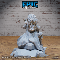 Rear view of a seated bard miniature showing flowing hair cascading over shoulders, detailed textured coat, and a faceted multi-chunk rocky scenic base. Sculpt by Epic Miniatures.