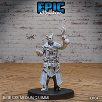 Grinning tiefling male with small curved horns, raising a round potion bottle crowned with conjured flames in one hand while the other hangs loose at his side, wearing a long layered coat with shoulder armour, belt pouches, and tool straps. Sculpt by Epic Miniatures.