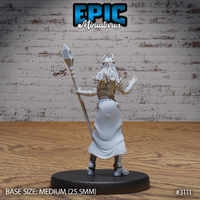Female wizard seen from behind, long flowing hair cascading over spiked pauldrons, staff raised in one hand, both arms extended as though mid-spellcast. Sculpt by Epic Miniatures.