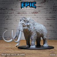 Front-quarter view of an unpainted grey resin woolly mammoth miniature by Epic Miniatures, showing swept curved tusks, deeply textured layered fur coat, and domed head with trunk at rest, mounted on a huge 76.5mm oval black base