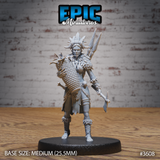 Front view of an unpainted grey resin 32mm miniature of a tribal female fisher — she wears a large feathered and horned headdress, a feathered cape, and carries a woven basket on her back, a bone-topped skull staff in one hand, and has a broad axe at her side. Printed on a medium round base.