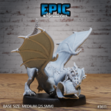 Unpainted grey resin White Dragon Wyrmling miniature by Epic Miniatures, front-facing three-quarter view showing the skull clutched in the jaws, hollow glassy eye socket, pronounced facial horns and spikes, spread wings framing the body, on a medium 25.5mm black base