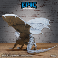 Rear three-quarter view of the unpainted grey resin Glacier Dragon miniature by Epic Miniatures — showing the full wingspan with ridged membranes and curved talon tips, heavily spined tail sweeping behind the creature, and thick dorsal scales along the back