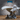 Unpainted grey resin Glacier Dragon miniature by Epic Miniatures, front three-quarter view — gargantuan dragon on a 102mm base crouching atop shattered rock, wings spread wide, one foreclaw raised, with detailed ridge scales, feathered wing membranes, and hooked wing tips
