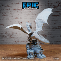 Unpainted grey resin Glacier Dragon miniature by Epic Miniatures, front-side view with both wings fully spread wide and the dragon's scaly body and horned head visible above a broken rocky ruin base — gargantuan scale, 102mm base