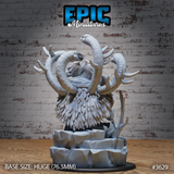Unpainted grey resin Primeval Idol variant miniature on a 76.5mm rocky base — a feathered owl-like body with a snarling draconic head, two massive serpents arching high above it, bare branches at the base. Epic Miniatures sculpt #3629.