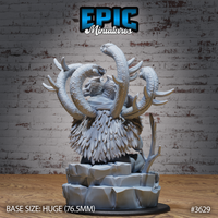 Unpainted grey resin Primeval Idol variant miniature on a 76.5mm rocky base — a feathered owl-like body with a snarling draconic head, two massive serpents arching high above it, bare branches at the base. Epic Miniatures sculpt #3629.