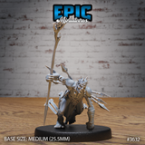 Front view of an unpainted grey resin 32mm miniature of the Old Heretic Crawling by Epic Miniatures — a hunched, muscular humanoid in a low crawling stance, carrying a tall bone staff topped with curved horns, his torso and back bristling with long ritual spines, wearing only a tattered loincloth and shin wrappings, mounted on a medium 25.5mm round base
