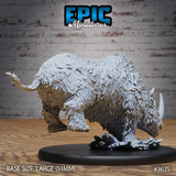 Unpainted grey resin woolly rhino miniature by Epic Miniatures, photographed from the rear-right — shaggy fur texture visible across haunches and back, charging pose with weight forward, ice scatter base detail, mounted on a large 51mm oval black base