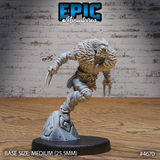 Unpainted grey resin Beast Master miniature by Epic Miniatures, shown from the front-right. The figure is mid-lunge, springing from a rocky base, with twin blades held in both hands, a wild flowing mane and beard, wrapped shins and forearms, and a belt hung with pouches. Medium 25.5mm base.