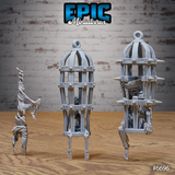 Three unpainted grey resin skeleton cage miniatures from Epic Miniatures — a ribbed birdcage on bone stilts with a huddled skeleton inside, a taller spike-collared cage containing an armoured skeleton, and a freestanding skeleton in a dramatic handstand pose, photographed on a wooden surface against a brick wall background